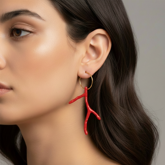 Cose E Bijoux Pantelleria gold hoop earrings featuring a long red resin coral branch pendant worn by a woman