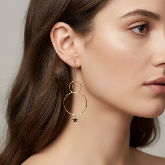Cose E Bijoux Bubbles asymmetric gold hoop earrings with a star charm worn on a model